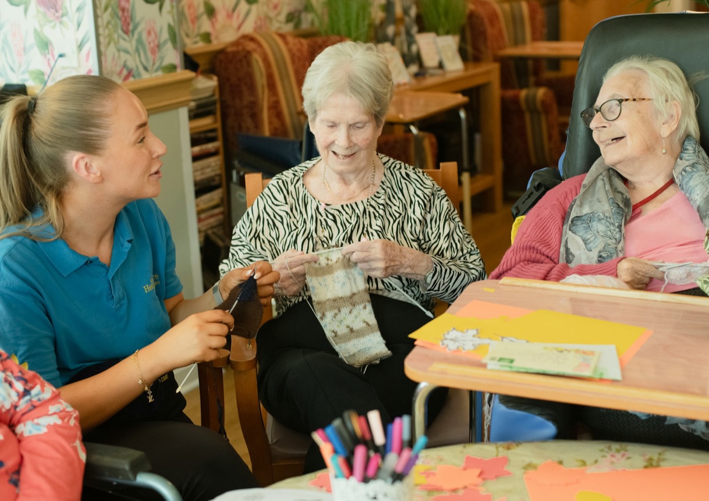 A care worker and older adults sharing a knitting activity