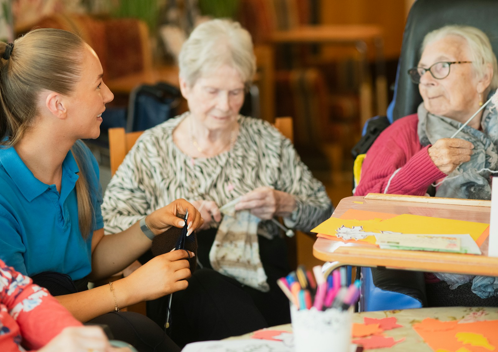 A care worker supporting older adults during a creative activity